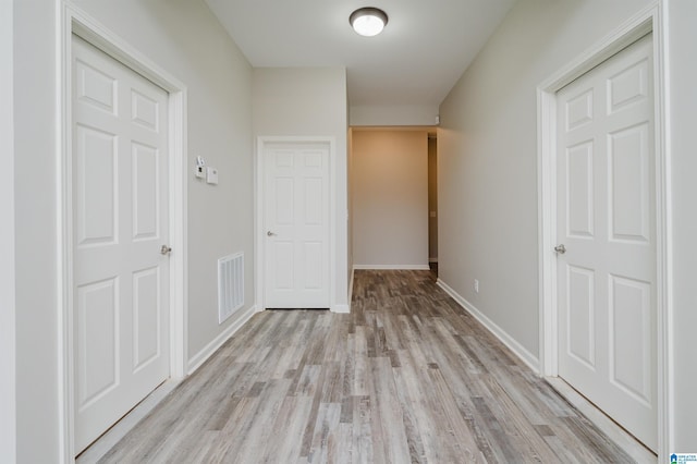 hallway with baseboards, visible vents, and light wood-style floors