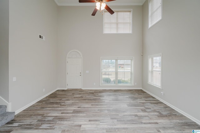 unfurnished living room with baseboards, visible vents, wood finished floors, stairs, and crown molding