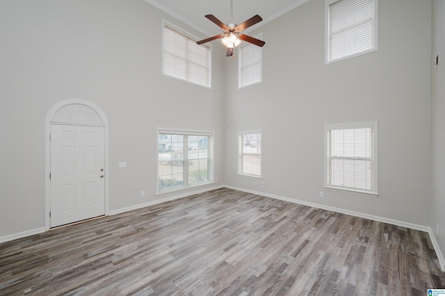 unfurnished living room with visible vents, a ceiling fan, ornamental molding, wood finished floors, and baseboards