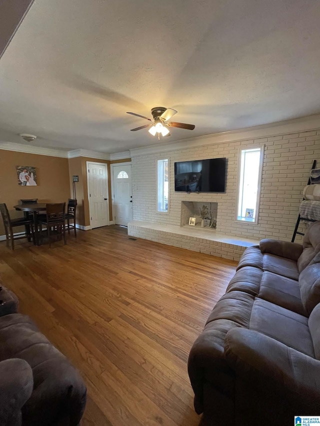 living room featuring brick wall, crown molding, a ceiling fan, and wood finished floors