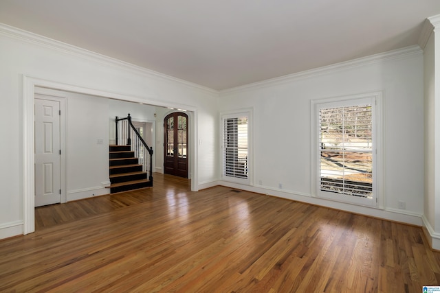 spare room featuring crown molding, visible vents, dark wood-type flooring, baseboards, and stairs