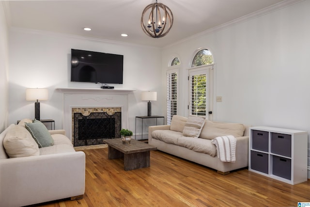 living area featuring recessed lighting, a fireplace, wood finished floors, ornamental molding, and an inviting chandelier