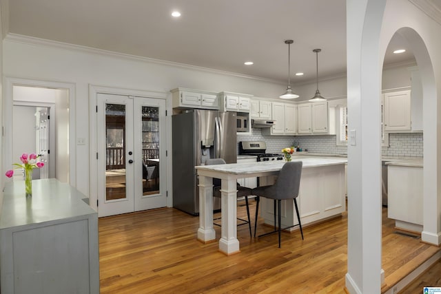 kitchen with hanging light fixtures, appliances with stainless steel finishes, white cabinetry, and light countertops