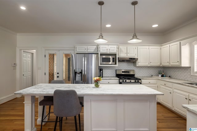 kitchen featuring stainless steel appliances, a kitchen island, light stone countertops, and under cabinet range hood