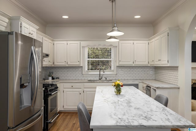 kitchen with a center island, hanging light fixtures, stainless steel appliances, white cabinetry, and a sink