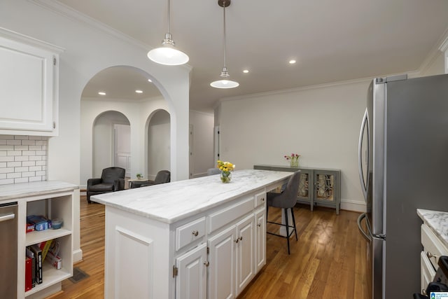 kitchen featuring a center island, pendant lighting, freestanding refrigerator, white cabinetry, and wood finished floors