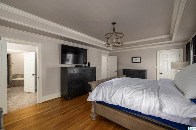 bedroom featuring ornamental molding, a tray ceiling, an inviting chandelier, and wood finished floors