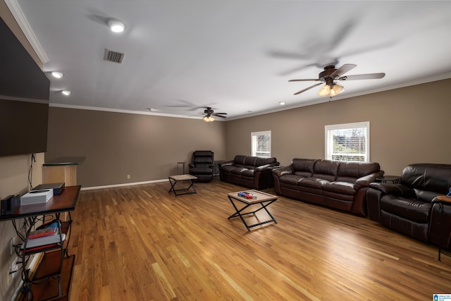 living area with light wood-type flooring, visible vents, crown molding, and baseboards