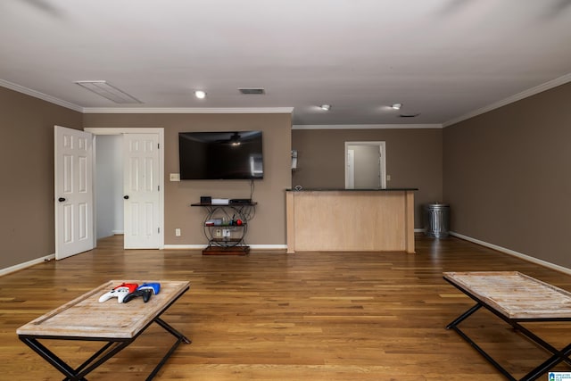 living room with ornamental molding, visible vents, baseboards, and wood finished floors