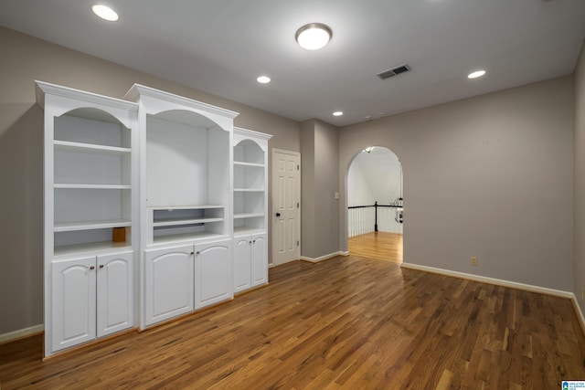 empty room featuring arched walkways, recessed lighting, visible vents, baseboards, and dark wood finished floors