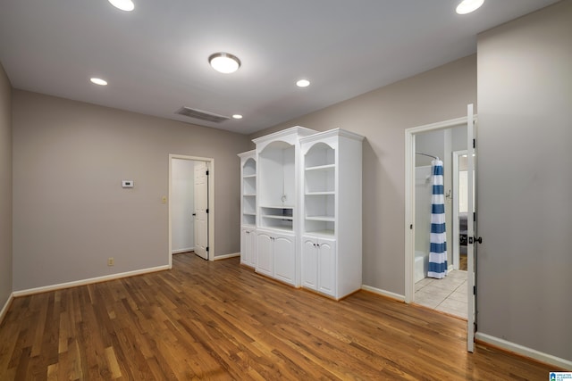 spare room with baseboards, visible vents, and wood finished floors