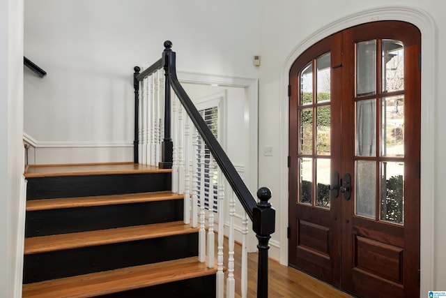 foyer entrance featuring stairs, arched walkways, wood finished floors, and french doors