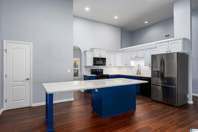 kitchen featuring a breakfast bar, a center island, light countertops, a high ceiling, and black appliances