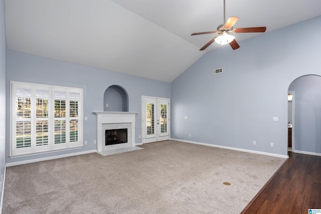 unfurnished living room featuring baseboards, visible vents, arched walkways, a ceiling fan, and a fireplace