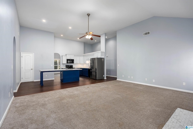 kitchen featuring arched walkways, white cabinets, a kitchen island, freestanding refrigerator, and light countertops