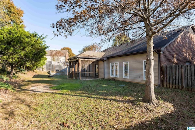 back of house featuring a sunroom, a fenced backyard, and a lawn