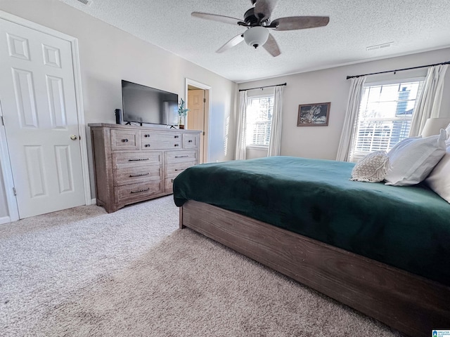 bedroom with visible vents, a ceiling fan, a textured ceiling, and light colored carpet