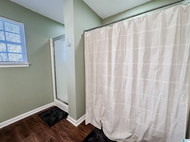 bathroom with a shower with shower curtain, wood finished floors, and baseboards