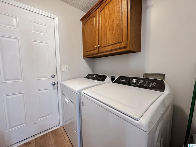 clothes washing area with light wood-style floors, cabinet space, a textured ceiling, and separate washer and dryer