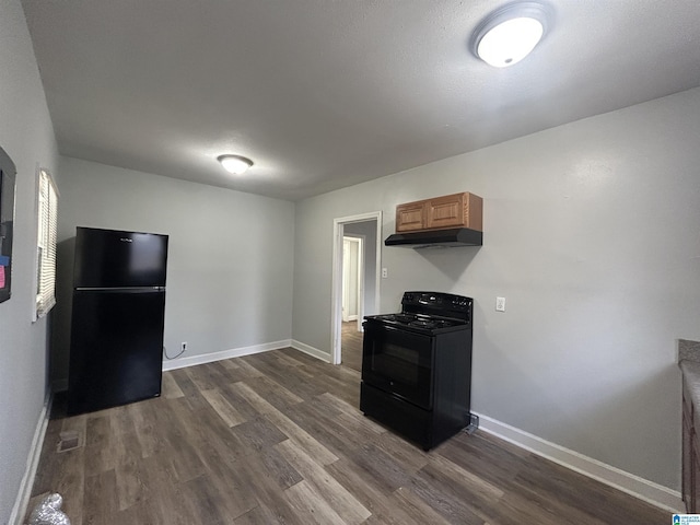 kitchen featuring dark wood-type flooring, baseboards, under cabinet range hood, and black appliances