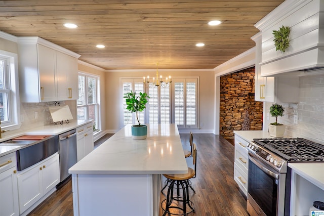 kitchen featuring white cabinets, ornamental molding, stainless steel appliances, light countertops, and pendant lighting