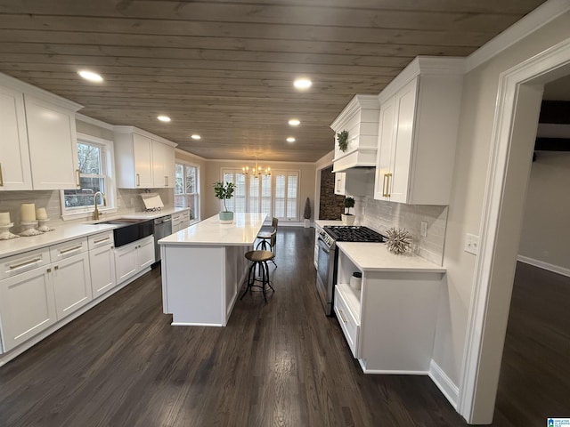 kitchen featuring stainless steel appliances, light countertops, white cabinets, a kitchen island, and a sink