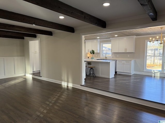 interior space with dark wood-style flooring, a sink, ornamental molding, beamed ceiling, and an inviting chandelier