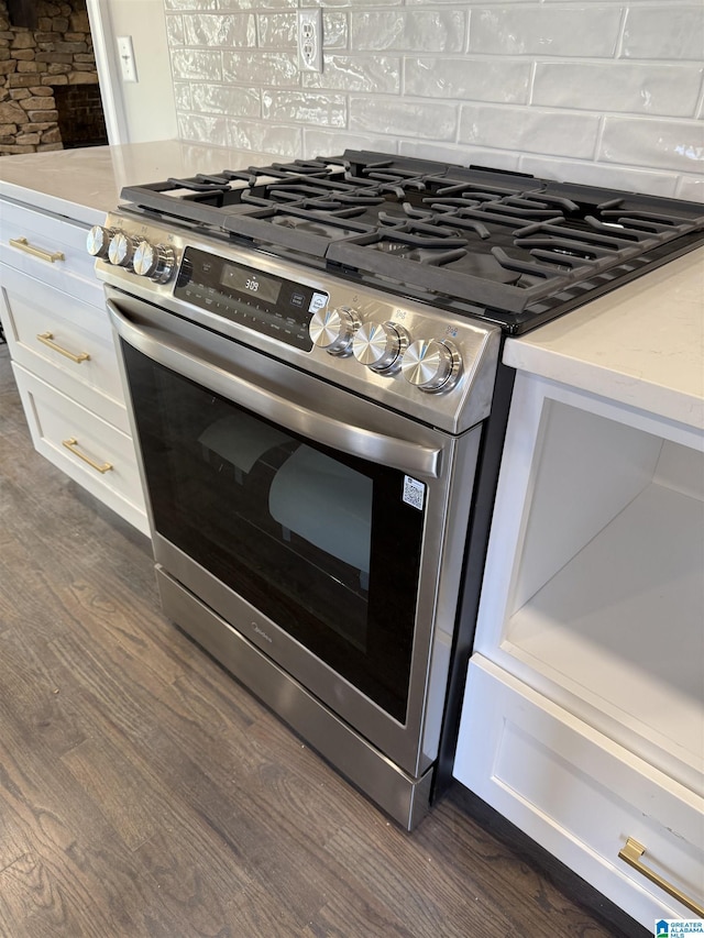 kitchen with dark wood-style floors, tasteful backsplash, light countertops, white cabinets, and stainless steel gas stove