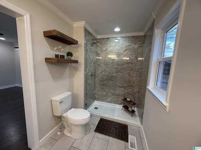 bathroom with visible vents, toilet, ornamental molding, baseboards, and walk in shower