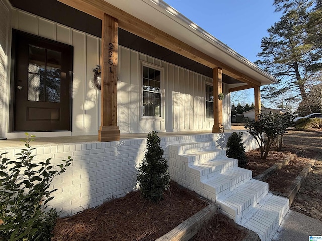 view of exterior entry with covered porch and board and batten siding