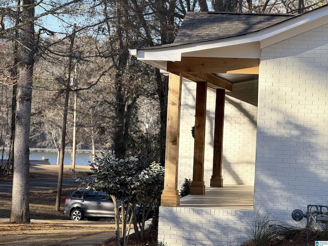 exterior space featuring brick siding and roof with shingles