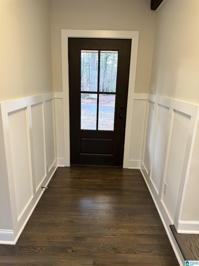 doorway with dark wood-style floors and a decorative wall