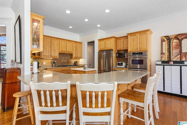 kitchen featuring a toaster, glass insert cabinets, appliances with stainless steel finishes, a kitchen breakfast bar, and a peninsula