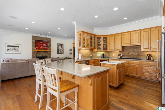 kitchen featuring dark wood-style floors, glass insert cabinets, open floor plan, a peninsula, and a kitchen bar