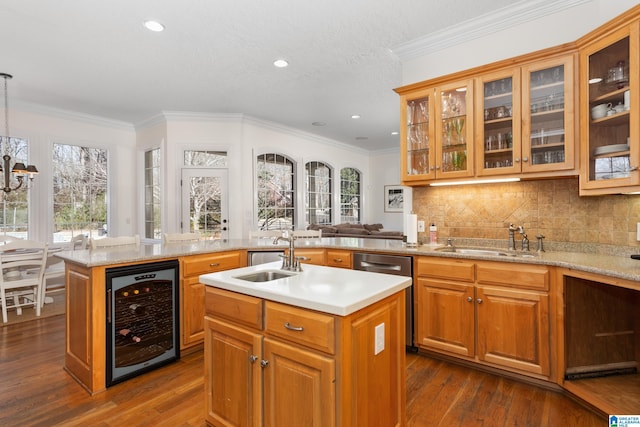 kitchen featuring dishwasher, wine cooler, hanging light fixtures, a kitchen island with sink, and a sink