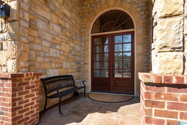 doorway to property with stone siding, french doors, and brick siding