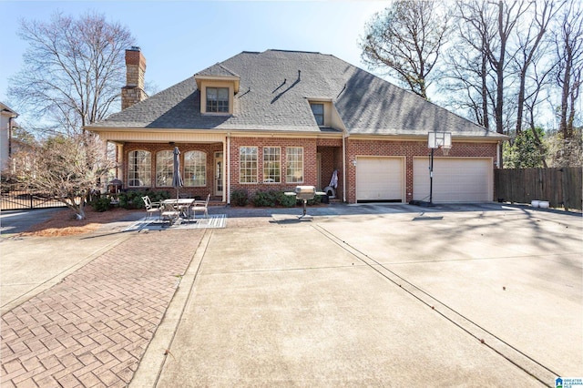 view of front of property with driveway, a garage, roof with shingles, fence, and brick siding