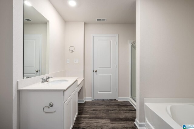 full bath featuring visible vents, vanity, a bath, and wood finished floors