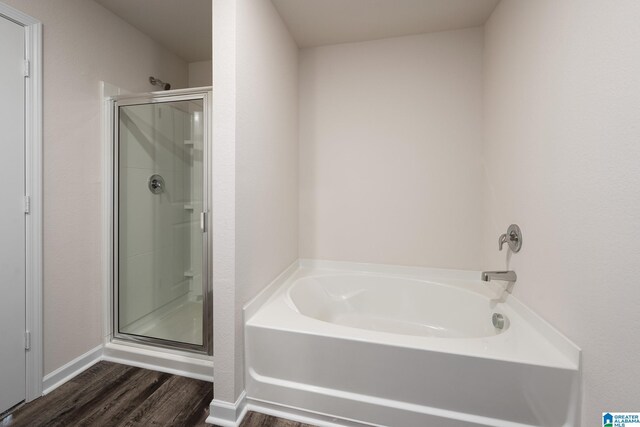 bathroom featuring a stall shower, a garden tub, and wood finished floors