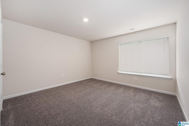 spare room featuring recessed lighting, dark carpet, visible vents, and baseboards