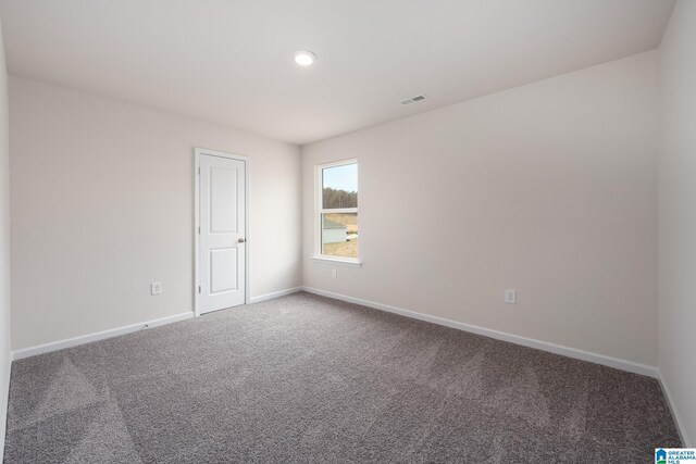 unfurnished room with carpet floors, visible vents, and baseboards