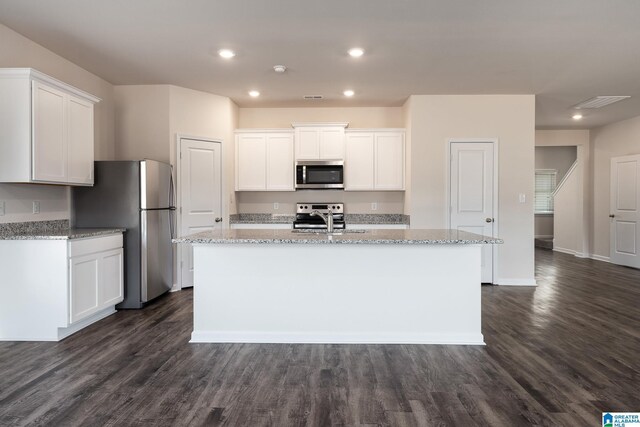 kitchen featuring white cabinets, an island with sink, light stone countertops, stainless steel appliances, and a sink