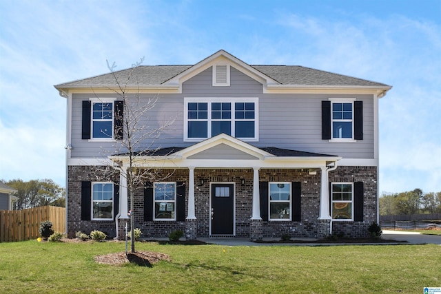 view of front of home featuring roof with shingles, brick siding, a front lawn, and fence