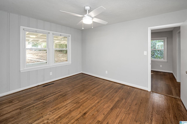 spare room featuring visible vents, dark wood-type flooring, ceiling fan, a textured ceiling, and baseboards