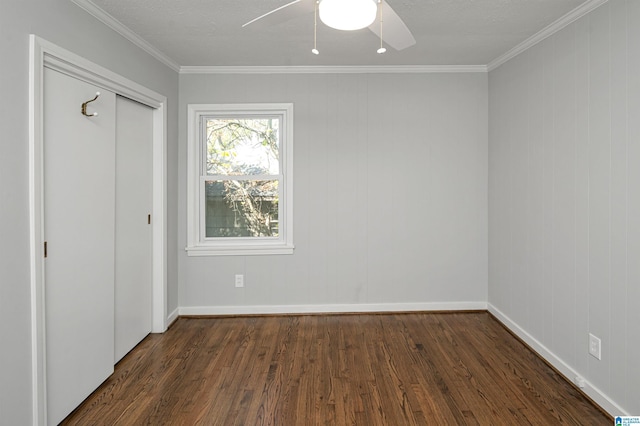 unfurnished bedroom with crown molding, a closet, baseboards, and dark wood-style flooring