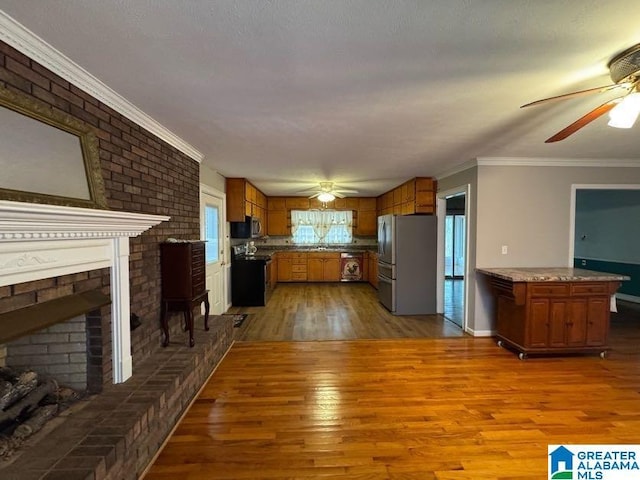 kitchen with brown cabinetry, freestanding refrigerator, a fireplace, and dark wood-style floors