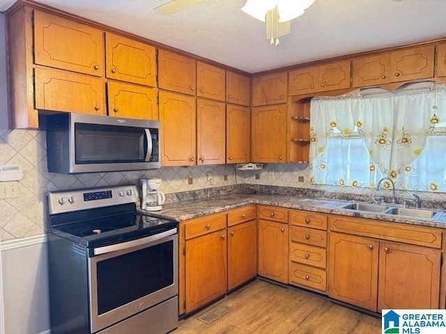 kitchen featuring tasteful backsplash, appliances with stainless steel finishes, a sink, and brown cabinets