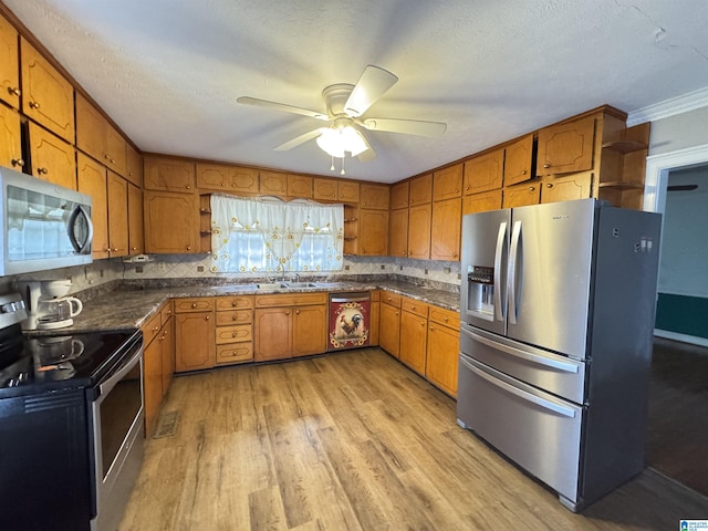 kitchen featuring dark countertops, light wood-style floors, appliances with stainless steel finishes, and brown cabinets