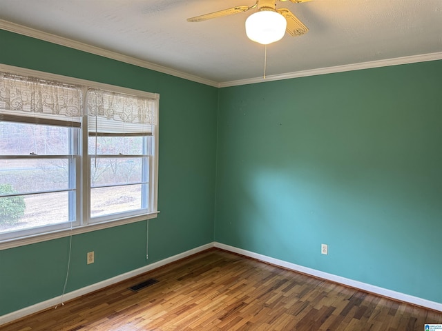 spare room with crown molding, visible vents, ceiling fan, wood finished floors, and baseboards