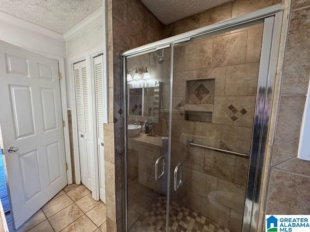 bathroom featuring a textured ceiling, ornamental molding, a closet, tile patterned floors, and a stall shower